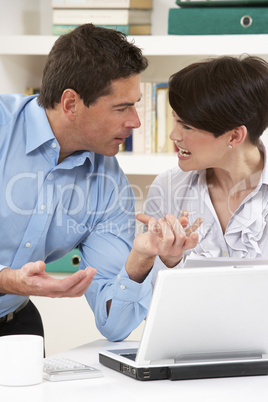 Arguing Couple Working From Home Using Laptop