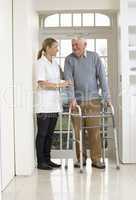 Carer Helping Elderly Senior Man Using Walking Frame
