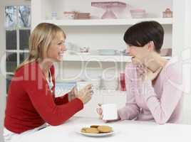 Two Women Enjoying Hot Drink In Kitchen
