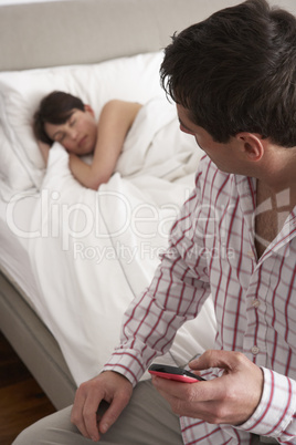 Suspicious Husband Checking Wife's Mobile Phone Whilst She Sleep