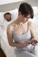 Suspicious Wife Checking Husband's Mobile Phone Whilst He Sleeps