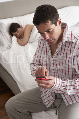 Suspicious Husband Checking Wife's Mobile Phone Whilst She Sleep