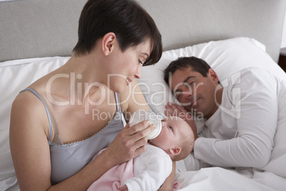 Mother Feeding Newborn Baby In Bed At Home