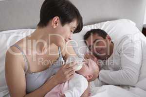 Mother Feeding Newborn Baby In Bed At Home