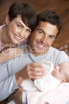 Portrait Of Parents Feeding Newborn Baby At Home