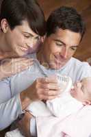 Portrait Of Parents Feeding Newborn Baby At Home