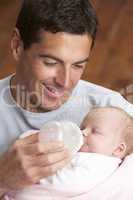 Portrait Of Father Feeding Newborn Baby At Home