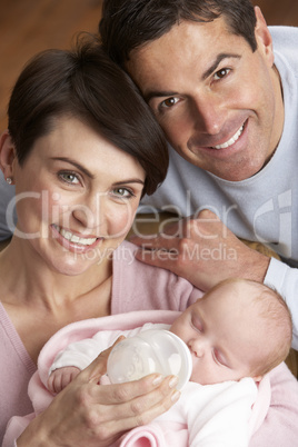 Portrait Of Parents Feeding Newborn Baby At Home