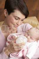 Portrait Of Mother Feeding Newborn Baby At Home