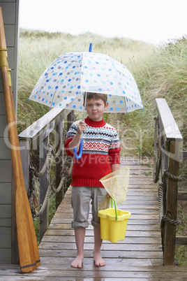 Boy standing on footbridge with umbrella