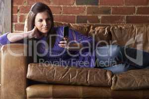 Young woman with phone on sofa