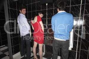 Woman and two men standing at mens urinal
