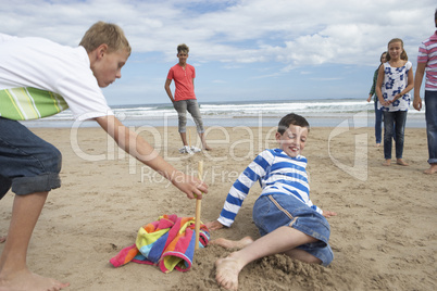 Teenagers playing baseball on beach