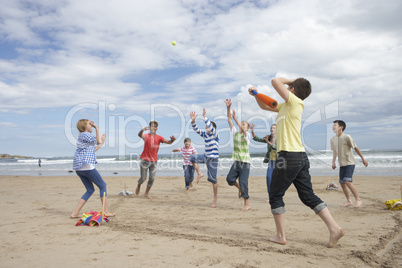Teenagers playing baseball on beach