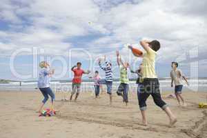 Teenagers playing baseball on beach