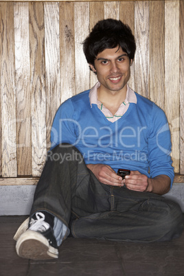 Young man sitting on floor with mobile phone