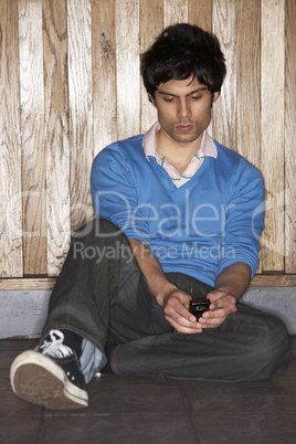 Young man sitting on floor with mobile phone