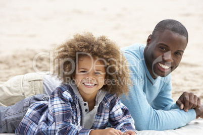 Father and son laying on beach