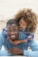 Father and son playing piggyback on beach