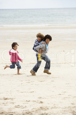 Happy children playing piggyback on beach