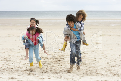 Happy children playing piggyback on beach