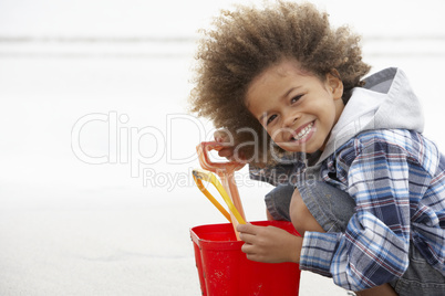 Happy boy at beach with bucket and spade
