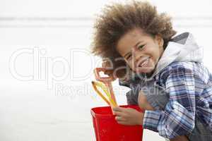 Happy boy at beach with bucket and spade