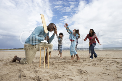 Family playing cricket on beach