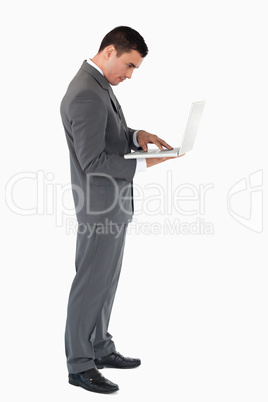 Standing businessman typing on his laptop against a white backgr