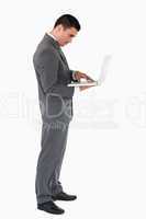 Standing businessman typing on his laptop against a white backgr