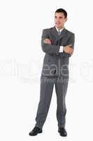 Businessman with arms folded looking confident against a white b