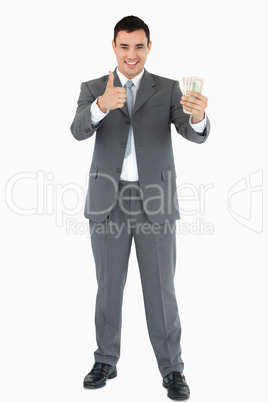 Businessman with banknotes giving thumb up