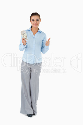 Businesswoman with banknotes giving thumb up