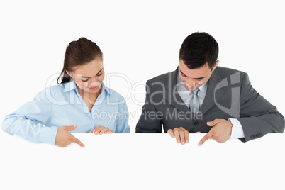 Business partners looking and pointing at sign they are holding