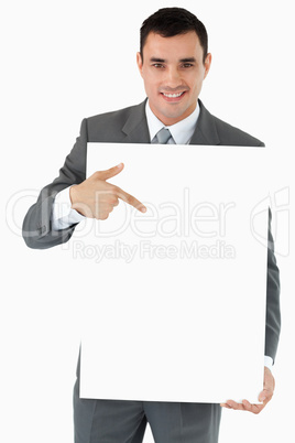 Smiling businessman pointing at the sign in his hands