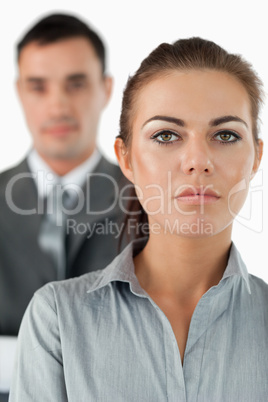 Close up of serious looking businesswoman with colleague behind