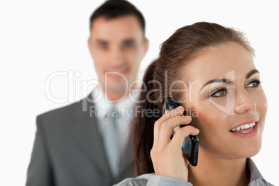 Close up of young businesswoman on the phone with colleague behi