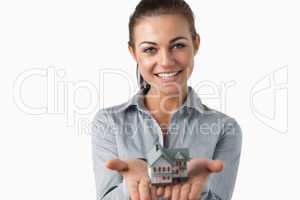 Female estate agent holding miniature house in her hands