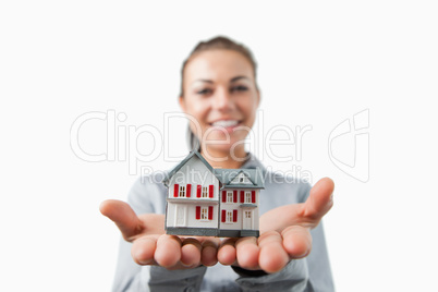 Miniature house being presented by female estate agent