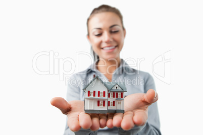 Miniature house being held by young female estate agent