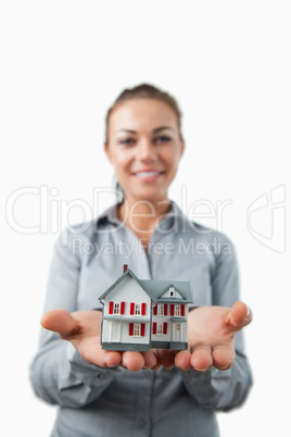 Miniature house being presented by young female estate agent