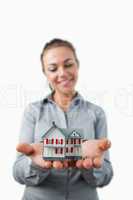 Miniature house being held by smiling female estate agent