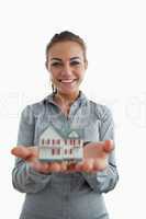 Young female estate agent presenting miniature house