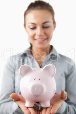 Close up of piggy bank being held by female bank assistant