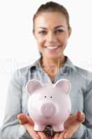 Close up of piggy bank being held by smiling female bank assista