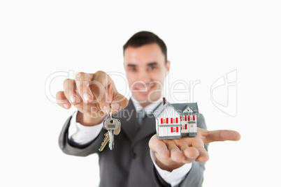 Close up of keys and miniature house being held by male estate a