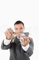 Miniature house and keys being presented by male estate agent