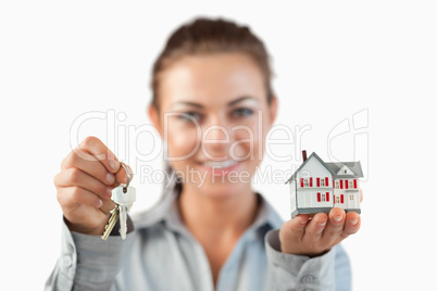 Keys and miniature house being presented by female estate agent