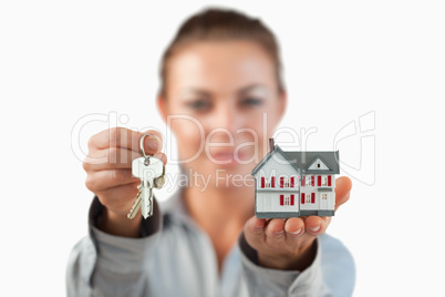 Miniature house and keys being presented by female estate agent