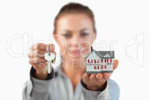 Miniature house and keys being presented by female estate agent